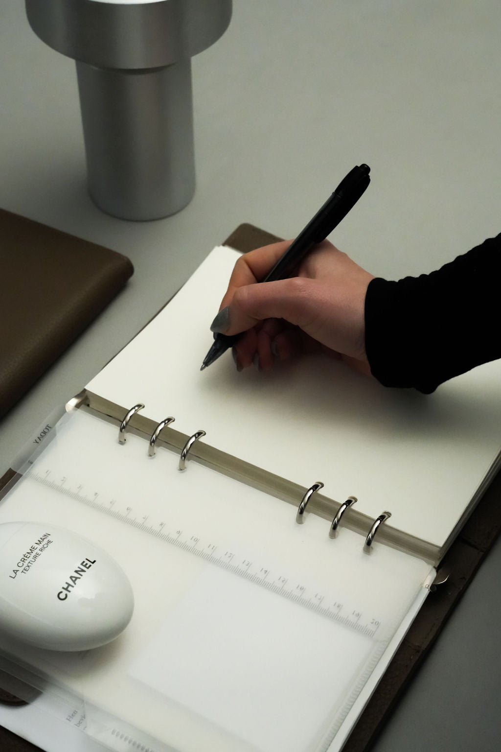 En kvindehånd der er i gang med at skrive på et blank stykke A5 papir i sin ALVINÉ Planner