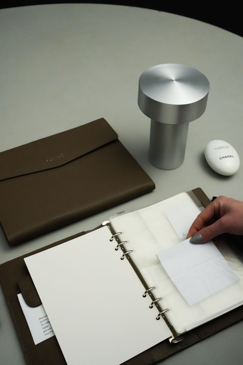 Kinde der er igang med at indsætte papir i sin dobbeltlomme insert i sin ALVINÉ Planner i Espresso. Ved siden af ligger en A5 Organizer i Espresso