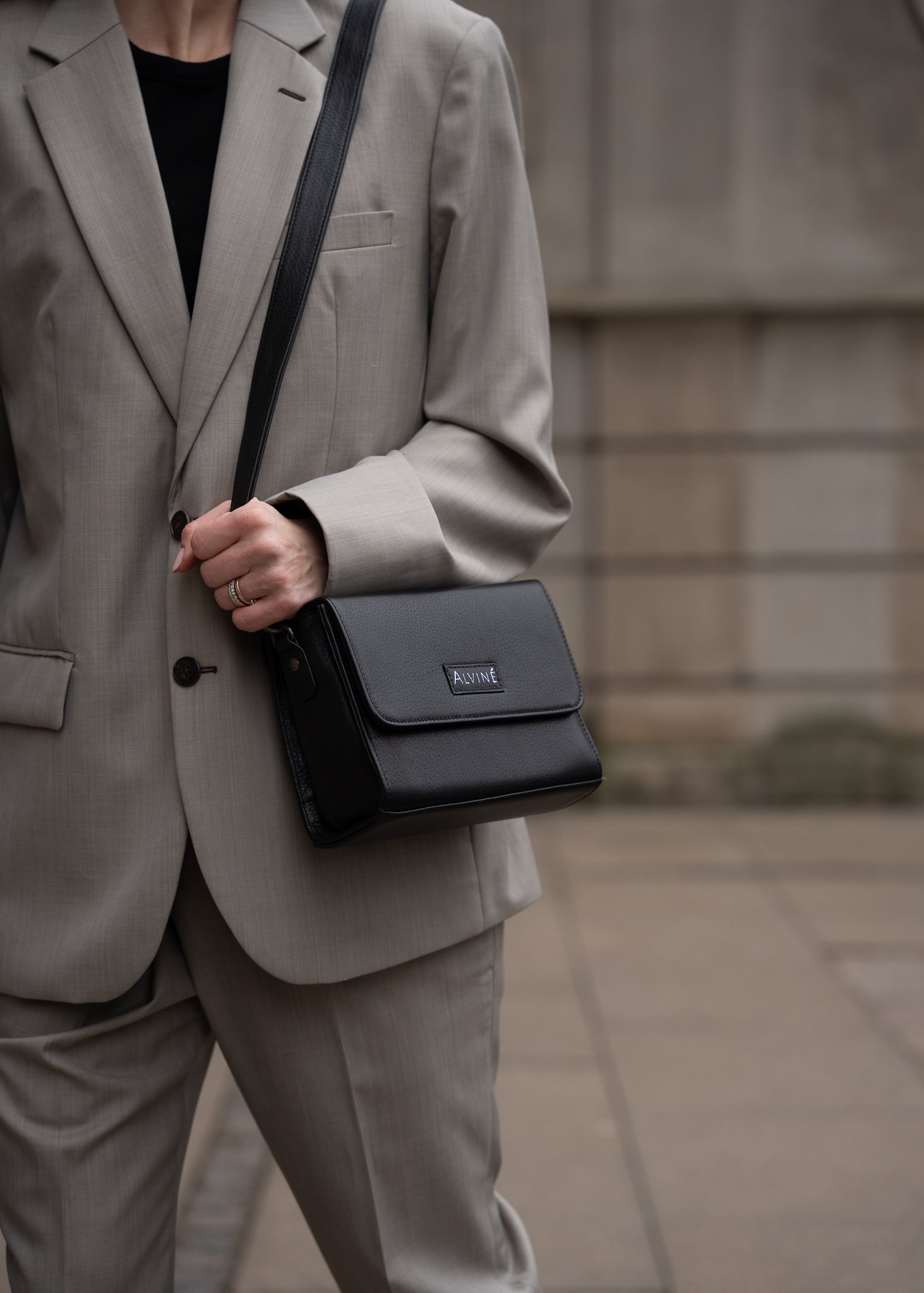 Close up af CC Pouch i Sort læder som crossbody på kvinde i gråt oversized jakkesæt