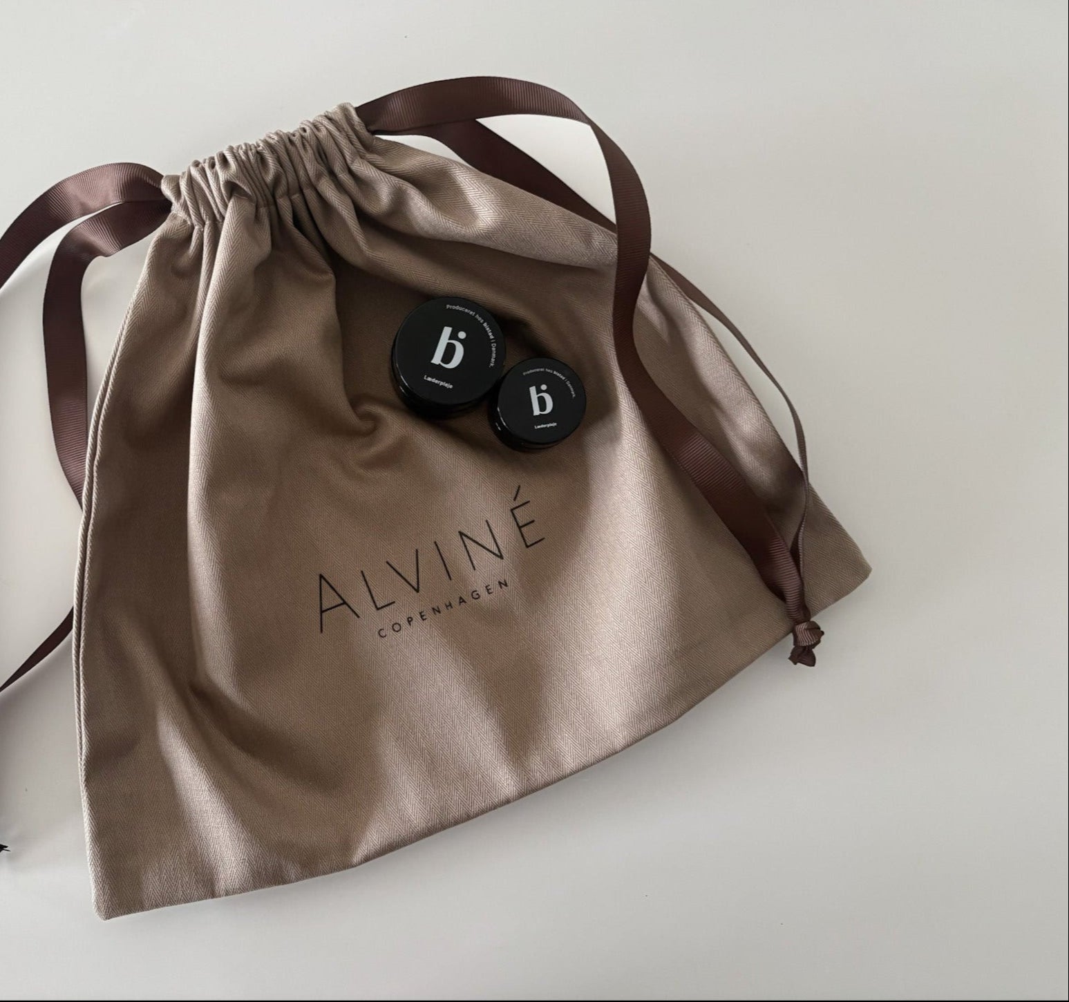 En dustbag med ALVINÉ logo på, som man modtager vores tasker i, sammen med to glas læderpleje fra danske BISTAD.