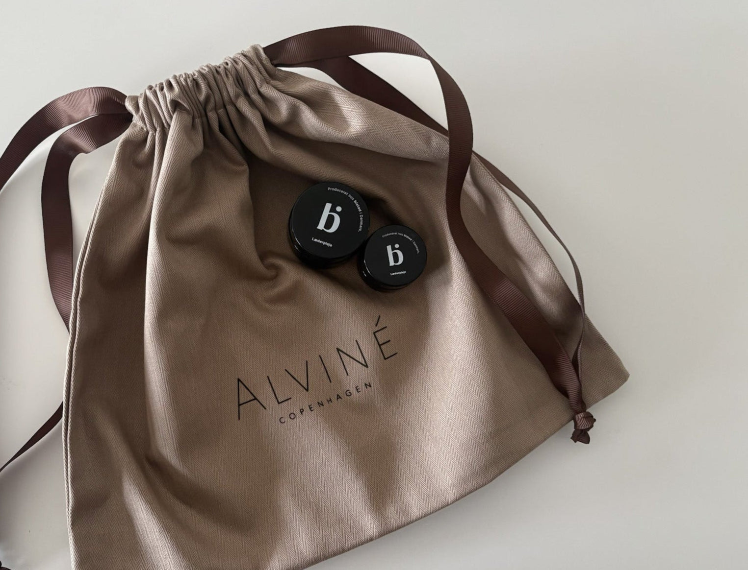 En dustbag med ALVINÉ logo på, som man modtager vores tasker i, sammen med to glas læderpleje fra danske BISTAD.