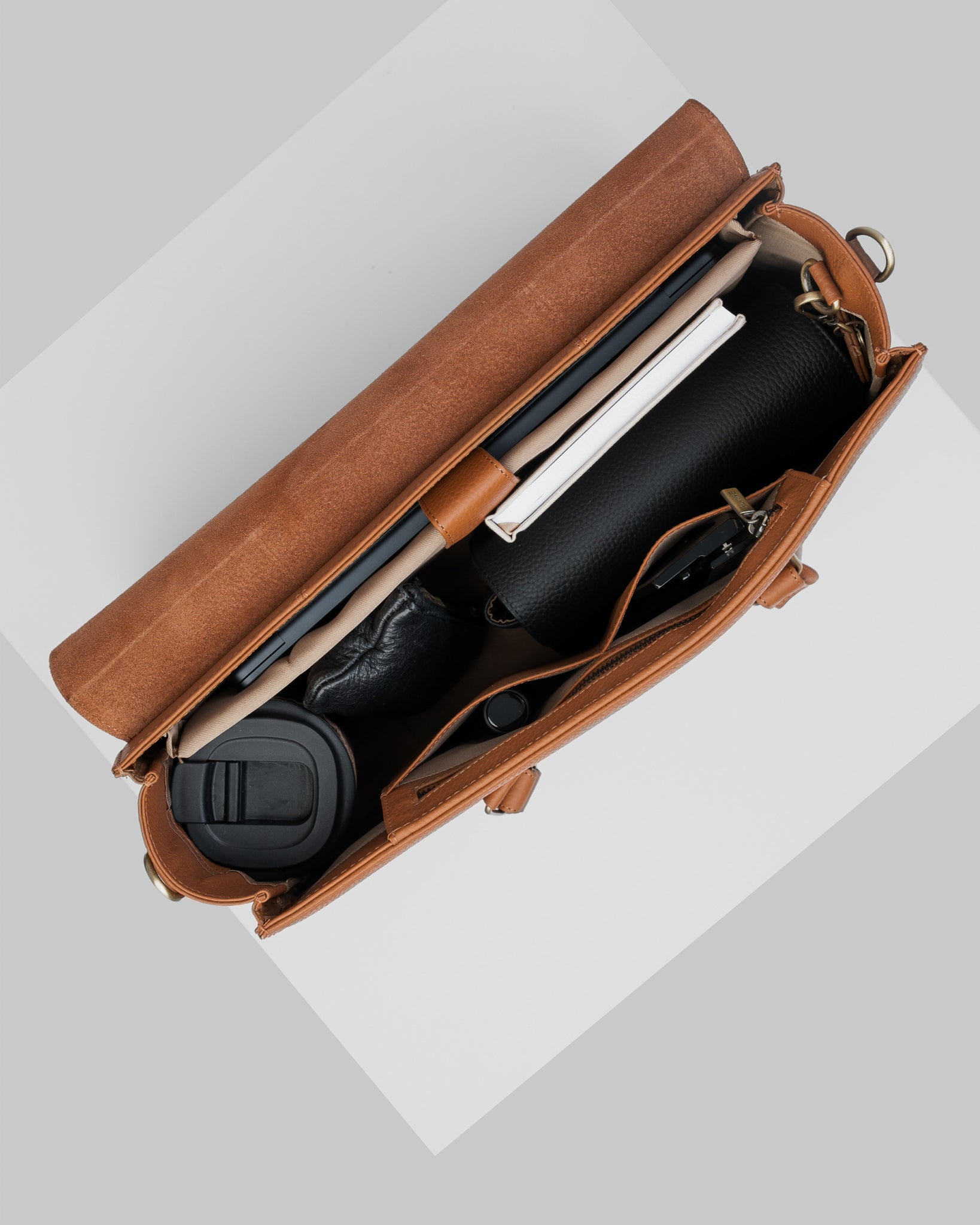 CC Arbejdstaske i Cognac læder set ovenfra med indhold som f.eks. to-go kop, laptop og CC Pouch i sort