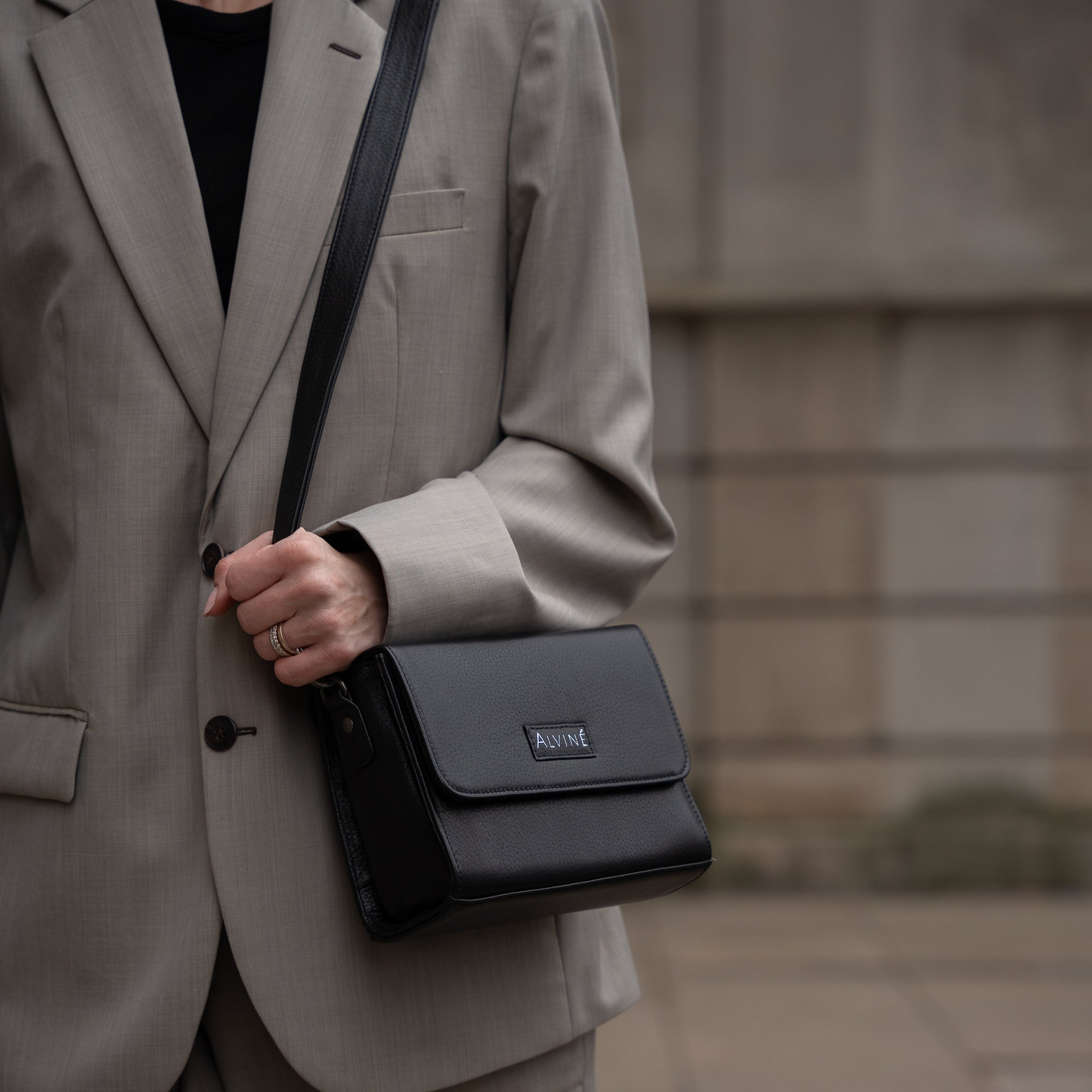 Close up af CC Clutch i Sort læder som crossbody på kvinde i oversized gråt jakkesæt