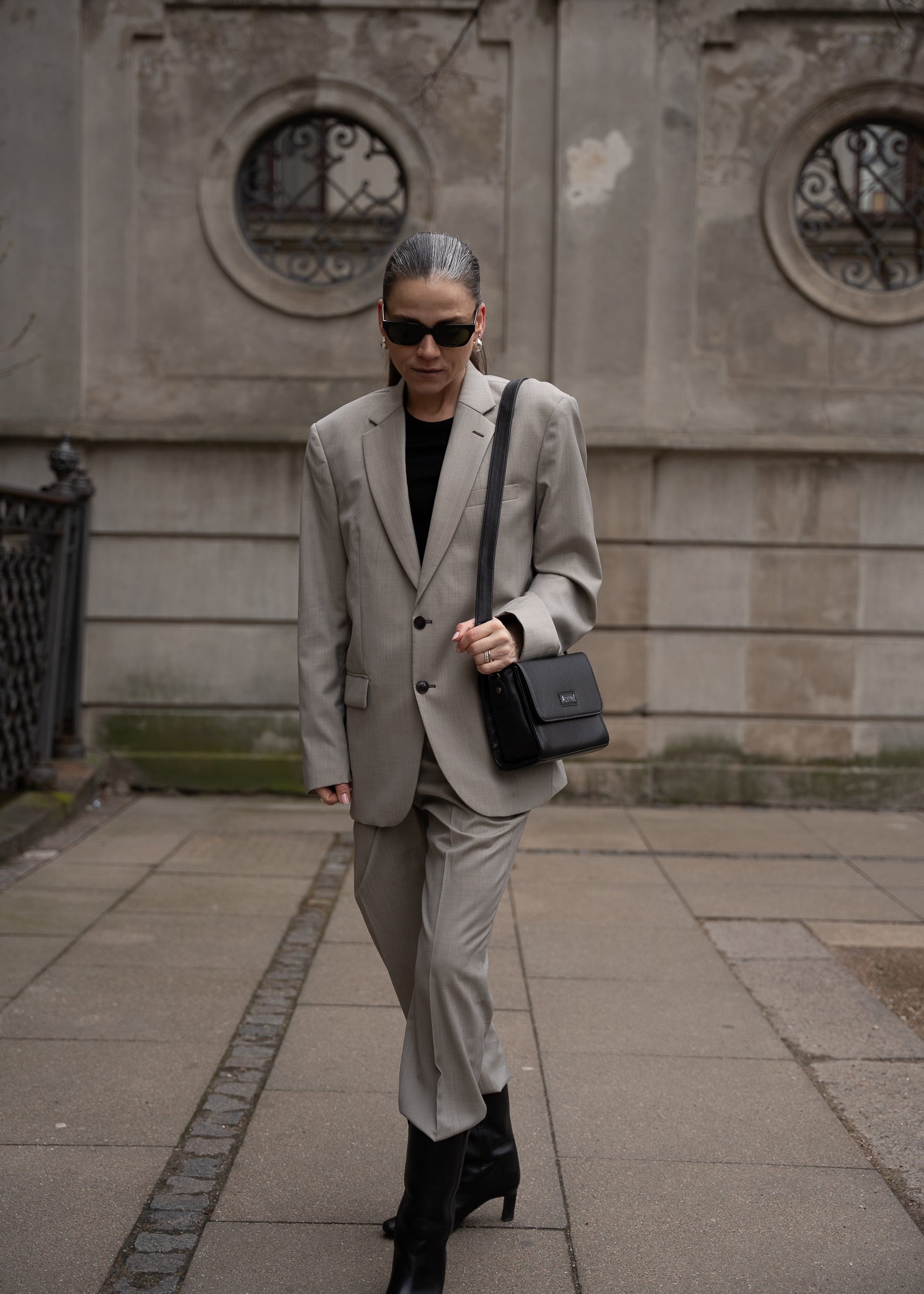 CC Clutch i Sort læder som crossbody på kvinde i gråt oversized jakkesæt og solbriller